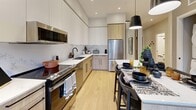 This well-appointed 2-bedroom, 2-bathroom residence at 140 Hollywood, CA offers a thoughtfully designed single-level floor plan that maximizes every square foot. Light oak hardwood flooring runs throughout, complementing the clean, modern aesthetic.

The open-concept kitchen and dining area is a standout feature, showcasing white upper cabinetry paired with warm wood lower cabinets, stainless steel appliances, a central island with pendant lighting, and a dining area ideal for entertaining. The living room is bathed in natural light from floor-to-ceiling sliding glass doors that open to a private balcony with neighborhood views, framed by elegant sheer drapery.

Both bedrooms are well-proportioned, with the primary bedroom featuring large windows with sheer curtains and access to ample closet space. The second bedroom doubles effectively as a home office, complete with a built-in closet featuring sliding doors. Each bathroom is finished with crisp white subway tile, including a soaking tub, and matte black fixtures for a contemporary touch.

Additional highlights include a dedicated entrance, in-unit laundry, and two closets. The overall ambiance is bright, clean, and modern, making this a functional and stylish urban residence.