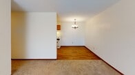 Located at 658 12th St SW in Forest Lake, Minnesota, this single-floor unit offers a practical and well-organized layout suited for comfortable everyday living. The galley-style kitchen is lined with warm honey-toned wood cabinetry on both sides, providing ample storage and counter space. It features a double sink, a white electric range, a refrigerator, and durable wood-look flooring that extends through the cooking area. A closet is conveniently accessible from within the kitchen corridor. Adjacent to the kitchen, the dining area is illuminated by an elegant chandelier, creating a welcoming atmosphere for meals and entertaining. The living area is generously sized, finished with neutral carpet and featuring a large window dressed with vertical blinds that allows for natural light. Baseboard heating runs along the perimeter, ensuring warmth throughout the colder Minnesota months. The bedrooms are carpeted and bright, each with windows that bring in natural light, along with baseboard heating for year-round comfort. The full bathroom includes a tiled tub-surround shower, a single vanity with wood cabinetry, tile flooring in a classic mosaic pattern, and clean white fixtures throughout. The overall palette of the unit is neutral and understated, offering a clean canvas throughout.