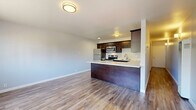 Located at 2500 Dana St in Berkeley, CA, this well-appointed one-bedroom, one-bathroom unit offers a thoughtfully designed layout making efficient use of its space. Wood-style plank flooring runs throughout the main living areas, lending a warm, cohesive feel from the entry hallway to the open-concept living and dining area.

The kitchen is a standout feature, boasting rich dark-walnut cabinetry with sleek hardware, light quartz countertops, a peninsula breakfast bar, and a full suite of stainless steel appliances including a refrigerator, electric range, and microwave. The open layout connects the kitchen seamlessly to the living and dining area, ideal for everyday functionality.

The bedroom is carpeted for comfort and features a wide bank of windows that frame lush treetop views, filling the room with natural light. Two closets provide ample storage throughout the unit.

The bathroom is finished with dark tile surround, a sliding glass-door tub/shower combo, wood-look flooring, a dark vanity with quartz countertop, and an undermount sink. A light-filled hallway with wall sconce connects all areas of the unit, completing this clean, modern residence in the heart of Berkeley.