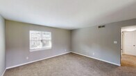 Located at 1220 Carriage House Ln in Gastonia, North Carolina, this well-appointed single-story home offers three bedrooms and three full bathrooms across a generously sized floor plan. The interior is finished with consistent neutral gray wall tones and plush wall-to-wall carpeting throughout the bedroom areas, creating a clean, cohesive aesthetic. The primary bedroom is notably expansive, offering ample space for large furnishings, and features multiple closets with classic panel-style white doors. Additional bedrooms are comfortably sized, each with windows that invite natural light and views of the surrounding neighborhood. A connecting hallway links the bedrooms and bathrooms, providing a logical and functional layout. The bathrooms are outfitted with white vanities, large mirrors, and tub-shower combinations featuring white tile surrounds and wood-look flooring, offering a tidy and practical design. The home includes an entrance that transitions smoothly into the living areas. A covered outdoor area opens to a view of a well-maintained green lawn and neighboring residences, providing a pleasant outdoor retreat. Overall, the home presents a straightforward, functional design with consistent finishes suited for comfortable everyday living.