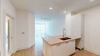 This well-designed one-bedroom, one-bathroom residence at 360 Village Dr in King of Prussia, PA offers a clean, modern aesthetic throughout its thoughtfully arranged single-floor layout. Light wood-style flooring flows seamlessly across the entire space, creating a warm and cohesive atmosphere.

The open-concept kitchen and living area serves as the heart of the home. The kitchen features sleek white cabinetry extending to the ceiling, a striking mosaic tile backsplash, stainless steel appliances including a French door refrigerator, microwave, and range, and a generous quartz-topped island with an undermount sink and gooseneck faucet — ideal for both cooking and casual dining. Recessed lighting illuminates the space efficiently.

The living area is bright and airy, highlighted by large sliding glass doors that invite natural light and provide views of the surrounding community. A dedicated closet with built-in shelving adds practical storage.

The bedroom is a comfortable retreat, offering a ceiling fan, a well-sized window with exterior views, and a clean, neutral palette. A dedicated closet provides ample storage.

The bathroom is finished with a warm quartz vanity countertop, white cabinetry with brushed gold hardware, an undermount sink, and a large gold-framed mirror, combining style and functionality in equal measure.