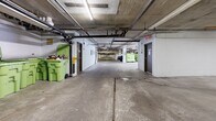 This expansive underground parking facility, located at 1200 Howie Ave in Coquitlam, BC, spans an impressive 1699 square meters on a single level. The space is characterized by its utilitarian design, with exposed concrete ceilings and floors, and white-painted brick walls. Numerous parking spots are clearly marked with large yellow numbers, accommodating various vehicle sizes. The facility's infrastructure is visible, with exposed pipes, electrical conduits, and lighting fixtures running along the ceiling. Security features include a gated entrance and strategically placed signage. The parking area is well-lit with fluorescent lighting, enhancing visibility and safety. Additional amenities include designated areas for bicycle storage and large waste containers. The layout is designed for easy navigation, with wide lanes and support columns spaced to maximize parking efficiency. This functional space prioritizes practicality and secure vehicle storage for residents or employees of the associated building.
