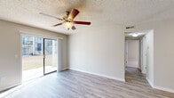 Located at 1108 Saint Andrews Dr in Wilmington, NC, this single-floor home offers five bedrooms and two full bathrooms. The combined kitchen and living room area serves as the heart of the home, with the living room featuring plush carpeting, a ceiling fan, a wood-burning fireplace with a clean white mantle, and sliding glass door access to a private balcony with outdoor views. A second room also opens to a balcony, providing additional outdoor access and natural light. The kitchen is well-appointed with white shaker-style cabinetry, dark countertops, light wood-look flooring, stainless steel appliances including a range and refrigerator, and a built-in sink with a peninsula. The five bedrooms are carpeted and finished in neutral tones, with windows allowing natural light throughout. At least one bedroom features a walk-in closet. The two bathrooms include wood-look tile flooring, white vanity cabinetry, and a tub-shower combination. Textured ceilings are present throughout the home. Two hallways and two closets round out the functional layout, providing ample circulation and storage space across the well-organized floor plan.