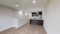 This thoughtfully designed single-floor space combines modern finishes with a functional open layout. Light wood-tone flooring runs throughout, creating a warm and cohesive aesthetic across all areas.

The kitchen is a standout feature, showcasing rich dark espresso cabinetry paired with striking marble-style countertops. A galley-style configuration provides ample prep and storage space, while stainless steel appliances — including a gas range, built-in microwave, and refrigerator — cater to everyday culinary needs. A white subway tile backsplash adds a clean, classic contrast to the dark cabinetry. A peninsula with a matching marble-top surface and an undermount sink extends into the open living area, making it ideal for casual dining or entertaining.

The living area is bright and open, benefiting from recessed lighting and a large window that frames views of the surrounding greenery, allowing natural light to fill the space. A wall-mounted electrical panel is discreetly integrated into the layout.

The bedroom is a comfortable, well-lit room with recessed lighting, a wide window overlooking a landscaped outdoor setting, and a wall-mounted HVAC unit for year-round climate control.

The bathroom features a sleek walk-in shower with a frameless sliding glass enclosure, tile surround, and a built-in bench, complemented by neutral tile flooring and clean white fixtures throughout.