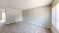 Located at 2050 S Ridgewood Ave in South Daytona, Florida, this two-story, two-bedroom, two-bathroom home offers a functional and straightforward layout spread across two floors. The ground floor hosts the main living areas, including a living room with natural light from a front-facing window, wood-look flooring near the entry, and a galley-style kitchen. The kitchen features white cabinetry extending to the upper walls, light stone countertops, a stainless steel sink, and appliances including a white range and black refrigerator, all set on light wood-look flooring with overhead lighting. A full bathroom on this level includes a tub/shower combo with white tile surround and a vanity with cabinet storage. A staircase connects the two floors, leading to the upper level where both bedrooms are located. The primary bedroom is generously sized, featuring plush carpet, a ceiling fan with light, a window with vertical blinds, and a wide wall of bifold louvered closet doors providing ample storage. The second bedroom also features carpet, a window with natural light, a textured ceiling, and its own bifold closet. A second full bathroom serves the upper level. Both floors feature textured ceilings throughout.