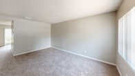 Located at 2050 S Ridgewood Ave in South Daytona, Florida, this two-story, two-bedroom, two-bathroom home offers a functional and straightforward layout spread across two floors. The ground floor hosts the main living areas, including a living room with natural light from a front-facing window, wood-look flooring near the entry, and a galley-style kitchen. The kitchen features white cabinetry extending to the upper walls, light stone countertops, a stainless steel sink, and appliances including a white range and black refrigerator, all set on light wood-look flooring with overhead lighting. A full bathroom on this level includes a tub/shower combo with white tile surround and a vanity with cabinet storage. A staircase connects the two floors, leading to the upper level where both bedrooms are located. The primary bedroom is generously sized, featuring plush carpet, a ceiling fan with light, a window with vertical blinds, and a wide wall of bifold louvered closet doors providing ample storage. The second bedroom also features carpet, a window with natural light, a textured ceiling, and its own bifold closet. A second full bathroom serves the upper level. Both floors feature textured ceilings throughout.