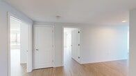 This single-floor residence offers a thoughtfully organized layout encompassing one bedroom, two bathrooms, a combined dining and living area, a dedicated living room, kitchen, and connecting hallway. The overall footprint provides a comfortable sense of spaciousness throughout.

The expansive living and dining area is a standout feature, characterized by large floor-to-ceiling windows fitted with vertical blinds that flood the space with natural light and offer open exterior views. Light-toned hardwood flooring runs throughout the main living areas, contributing to a bright, clean aesthetic. Track lighting in the dining area provides focused illumination.

The galley-style kitchen is efficiently designed with light wood cabinetry, dark granite countertops, tile flooring, and stainless steel appliances including a refrigerator, range, and dishwasher — offering a functional and modern workspace.

The bedroom features light hardwood floors, crisp white panel doors, and connects seamlessly to the hallway. Both bathrooms are finished with tile flooring; one includes a full soaking tub with a surround enclosure and a warm wood-toned vanity with a mirrored medicine cabinet above. Throughout, the unit maintains a neutral, light gray and white color palette, creating a clean, contemporary ambiance.