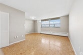 Located at 5-15 Harding Ave in Toronto's Mount Dennis neighbourhood, this well-laid-out one-bedroom, one-bathroom unit offers a functional and comfortable living space across a single floor. Warm parquet flooring flows throughout the living room, bedroom, and hallway, lending the home a classic, timeless character.

The living room is generously proportioned, bathed in natural light through large floor-to-ceiling windows that frame sweeping views of the Toronto skyline and surrounding greenery. A baseboard heating system runs along the perimeter, ensuring year-round comfort.

The kitchen is bright and clean, featuring white cabinetry extending to the ceiling for ample storage, marble-look countertops, a stainless steel electric range, and white tile flooring — a practical and stylish space for everyday cooking.

The bedroom is a comfortable retreat, benefiting from its own window with open city views, parquet flooring, and neutral-toned walls that create a calm atmosphere. The full bathroom is finished in crisp white, with classic mosaic tile flooring, a full soaker tub, and clean, simple fixtures.

A connecting hallway ties all rooms together efficiently, contributing to the unit's smart and cohesive layout. Overall, the space offers a bright, neutral palette with functional finishes throughout.