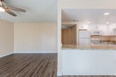 This single-floor residence offers a thoughtfully designed layout that balances functionality and comfort throughout its living spaces. The living area greets residents with warm hardwood-style flooring, a ceiling fan, and generous natural light streaming through sliding glass doors fitted with vertical blinds and additional windows — creating a bright, welcoming atmosphere that extends toward the front entry.

The kitchen is a standout feature, offering white shaker-style cabinetry, granite countertops with subtle earth-tone veining, and a full suite of white appliances including a refrigerator, electric range, and built-in microwave. Recessed lighting illuminates the space efficiently, while a peninsula with a matching granite surface connects the kitchen to the main living area, enhancing the open feel.

The bedroom is generously proportioned, finished with plush carpet, a modern flush-mount light fixture, and a window providing natural light and outdoor views. A dedicated walk-in closet offers ample storage.

The bathroom features a white vanity with granite countertops, hardwood-style flooring, and a full tub-and-shower combination. Textured ceilings are consistent throughout, and the warm neutral wall tones unify the overall aesthetic.