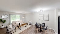 This single-floor residence offers a thoughtfully designed layout with a neutral color palette and modern finishes that create a clean, cohesive aesthetic throughout. The open-concept living and dining area is anchored by warm wood-look flooring, a sliding glass door with vertical blinds that invites abundant natural light and views of lush greenery, and a contemporary multi-arm ceiling fixture. The space comfortably accommodates both a seating arrangement and a dining set, making it ideal for everyday living and entertaining. The kitchen features crisp white shaker-style cabinetry with matte black hardware, striking marble-look quartz countertops, and stainless steel appliances including a range, over-the-range microwave, and dishwasher. Two bedrooms provide restful retreats, each carpeted for comfort and equipped with windows that allow natural light. One bedroom includes a sliding-door closet with a full rod and shelf system, while the other benefits from a serene wooded view. The full bathroom is finished with a gray vanity, white countertop, framed mirror, and a tub-shower combination. Throughout the residence, consistent neutral tones and durable flooring choices reinforce a modern, move-in-ready appeal.