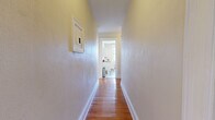 Located on West Sycamore Street in Pittsburgh's charming Mount Washington neighborhood, this 2-bedroom, 1-bathroom unit offers a generously sized single-floor layout with a thoughtful arrangement of rooms connected by two hallways. The living area showcases warm hardwood flooring, a ceiling fan, and arched windows that invite natural light while providing views of the surrounding greenery. A decorative chandelier adds character to the adjacent dining or sitting area, which also features a cast-iron radiator and beautiful arched window trim reflecting the home's classic architectural roots. The kitchen is well-appointed with white cabinetry, butcher block countertops, tile flooring, a stainless steel refrigerator, and a range, along with a built-in storage unit that adds functional charm. Both bedrooms are carpeted and generously proportioned, each featuring ceiling fans, multiple windows for ample natural light, and cast-iron radiators that speak to the home's historic character. The primary bedroom is notably spacious. The bathroom is clean and bright, featuring a combination tub and shower with a crisp white tile surround, classic penny-tile flooring, and a window for ventilation. Throughout the unit, warm neutral tones and traditional architectural details create a comfortable and inviting atmosphere.