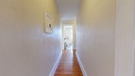Located on West Sycamore Street in Pittsburgh's charming Mount Washington neighborhood, this 2-bedroom, 1-bathroom unit offers a generously sized single-floor layout with a thoughtful arrangement of rooms connected by two hallways. The living area showcases warm hardwood flooring, a ceiling fan, and arched windows that invite natural light while providing views of the surrounding greenery. A decorative chandelier adds character to the adjacent dining or sitting area, which also features a cast-iron radiator and beautiful arched window trim reflecting the home's classic architectural roots. The kitchen is well-appointed with white cabinetry, butcher block countertops, tile flooring, a stainless steel refrigerator, and a range, along with a built-in storage unit that adds functional charm. Both bedrooms are carpeted and generously proportioned, each featuring ceiling fans, multiple windows for ample natural light, and cast-iron radiators that speak to the home's historic character. The primary bedroom is notably spacious. The bathroom is clean and bright, featuring a combination tub and shower with a crisp white tile surround, classic penny-tile flooring, and a window for ventilation. Throughout the unit, warm neutral tones and traditional architectural details create a comfortable and inviting atmosphere.