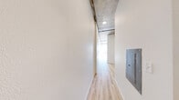 Located at 1942 S Fawcett Ave in Tacoma, WA, this one-bedroom, one-bathroom unit offers a well-designed layout across a single floor. The space showcases an industrial-modern aesthetic highlighted by exposed concrete ceilings, light hardwood-style flooring throughout, and crisp white walls that maximize brightness.

The open-concept kitchen and living area serves as the heart of the unit. The kitchen is outfitted with rich dark wood cabinetry, a mosaic tile backsplash, stainless steel appliances including a gas range and built-in microwave, and a full-size refrigerator — providing both style and functionality.

The living area flows naturally from the kitchen and leads to the bedroom, which features a large picture window that invites abundant natural light and offers open views of the surrounding Tacoma neighborhood and sky. The bedroom also includes a dedicated closet for storage.

A hallway connects the main living spaces to the bathroom and a dedicated laundry area equipped with a stacked washer and dryer unit — a convenient in-unit amenity. The hallway also houses an electrical panel, keeping utilities neatly organized.

Overall, the unit presents a clean, modern feel with functional urban design elements, making efficient use of its compact footprint while maintaining a bright and comfortable atmosphere.