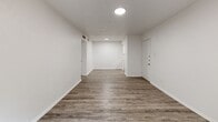 Located at 3504 Fawn Valley Dr in Dallas, TX, this two-bedroom, two-bathroom single-floor home offers a clean, modern aesthetic throughout. Consistent grey-toned vinyl plank flooring flows seamlessly across all rooms, complemented by crisp white walls and white trim that create a bright, cohesive feel.

The living area is open and well-lit, connected by a hallway that leads to the bedrooms and bathrooms. The spacious primary bedroom is a standout feature, offering generous square footage and direct access to a private outdoor balcony through a sliding glass door — bringing in natural light and views of lush greenery. The second bedroom also benefits from natural light via a window with outdoor views.

Both bathrooms are finished in white with updated vanities featuring light-toned countertops, integrated sinks, and multi-bulb vanity lighting. One bathroom includes wood-look flooring and an open vanity design, while the second features tile flooring and a full tub and shower combination.

A dedicated closet and hallway provide practical storage and circulation. Ceiling light fixtures with recessed or flush-mount designs illuminate each room efficiently. The overall design is clean, minimal, and move-in ready, offering a comfortable living environment in a well-connected Dallas neighborhood.
