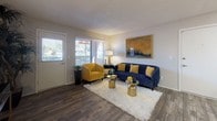 Located at 4500 E Sunrise Dr in the desirable Tucson, AZ 85718 area, this single-floor residence offers a thoughtfully designed layout with a cohesive, contemporary aesthetic throughout. The living room serves as the heart of the home, featuring rich wood-look flooring, a textured ceiling, and generous natural light streaming through wide horizontal-blind windows. A bold navy sofa and mustard-yellow accent chair provide a striking color palette that carries through the entire space.

The galley-style kitchen is well-appointed with gray cabinetry, brushed nickel hardware, light speckled countertops, a stainless steel sink, and black appliances including a range and refrigerator. It flows seamlessly into a dining area, where a glass-top table with navy and gold seating makes for an inviting setting.

The bedroom is a restful retreat with carpeted flooring and ample room for furnishings. The bathroom features gray cabinetry with a speckled countertop vanity, a large mirror, wood-look tile flooring, and a tiled shower-tub combo accented with warm gold curtain tones. Throughout the space, the warm neutral wall tones and carefully chosen décor create an inviting, well-balanced ambiance that is both functional and visually appealing.