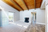 Located at 10700 E Dartmouth Ave in Denver, CO, this two-bedroom, one-bathroom residence offers a thoughtfully designed single-floor layout. The living room immediately captivates with its soaring vaulted ceiling clad in warm wood planks and supported by exposed timber beams, creating a striking architectural focal point. A black-tiled fireplace anchors the space, while sliding glass doors open to a private balcony with outdoor views, flooding the room with abundant natural light. The flooring transitions from plush carpet in the living area to durable wood-look hardwood throughout the rest of the home. The kitchen is efficiently laid out with white shaker-style cabinetry, light stone-finish countertops, a stainless steel sink, and black appliances including a refrigerator and range. The two bedrooms are carpeted and offer generous closet storage, with the primary bedroom featuring direct access to the bathroom. The full bathroom includes a clean, white tub-shower combo with wood-look flooring. A hallway connects the bedroom wing to the main living areas, completing this well-organized and characterful home in the Denver metro area.