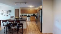 Located at 338 N Milwaukee St in Milwaukee, Wisconsin, this single-floor urban residence is situated in the heart of the city's dynamic East Town neighborhood. The unit is thoughtfully laid out, with distinct living zones that flow cohesively throughout the space.

The kitchen is a standout feature, outfitted with warm honey-toned cabinetry, dark granite countertops, and a full suite of stainless steel appliances including a refrigerator, oven, microwave, and dishwasher. A central island with bar-height seating provides additional prep space and casual dining options. Track lighting overhead and wood-look flooring throughout the kitchen and living areas add to the contemporary aesthetic.

The living room is generously sized and filled with natural light courtesy of floor-to-ceiling windows that frame views of the surrounding Milwaukee cityscape. A sliding glass door opens directly to a private balcony, enhancing the connection between indoor and outdoor living.

The bedroom continues the bright, open feel with large windows offering urban views and plush carpeting underfoot. The bathroom is finished with large-format dark tile flooring, a wood-toned vanity with ample storage, and a glass-enclosed walk-in shower, delivering a clean, modern aesthetic throughout.
