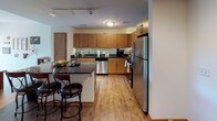 Located at 338 N Milwaukee St in Milwaukee, Wisconsin, this single-floor urban residence is situated in the heart of the city's dynamic East Town neighborhood. The unit is thoughtfully laid out, with distinct living zones that flow cohesively throughout the space.

The kitchen is a standout feature, outfitted with warm honey-toned cabinetry, dark granite countertops, and a full suite of stainless steel appliances including a refrigerator, oven, microwave, and dishwasher. A central island with bar-height seating provides additional prep space and casual dining options. Track lighting overhead and wood-look flooring throughout the kitchen and living areas add to the contemporary aesthetic.

The living room is generously sized and filled with natural light courtesy of floor-to-ceiling windows that frame views of the surrounding Milwaukee cityscape. A sliding glass door opens directly to a private balcony, enhancing the connection between indoor and outdoor living.

The bedroom continues the bright, open feel with large windows offering urban views and plush carpeting underfoot. The bathroom is finished with large-format dark tile flooring, a wood-toned vanity with ample storage, and a glass-enclosed walk-in shower, delivering a clean, modern aesthetic throughout.