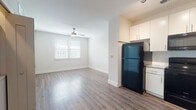 This single-floor unit offers a clean, modern design with an open-concept living and kitchen area at its core. The living space features smooth wood-look laminate flooring, neutral white walls, and a ceiling fan that enhances comfort and airflow. A window with horizontal blinds allows natural light to fill the room, creating a bright and welcoming atmosphere.

The kitchen flows seamlessly from the living area and is outfitted with white shaker-style cabinetry, granite countertops, a subway tile backsplash, and a stainless steel undermount sink. Black appliances, including a refrigerator, electric range, microwave, and dishwasher, provide a consistent and functional aesthetic.

A dedicated laundry closet houses a stacked washer and dryer unit, offering the convenience of in-unit laundry. The bedroom is carpeted for comfort and receives natural light through a window with blinds, offering a quiet and cozy retreat.

The bathroom is finished with light tile flooring, a granite-topped vanity with white cabinetry, and a full shower-tub combination with clean white tile surround. Throughout the unit, crisp white trim and neutral tones contribute to a cohesive, well-maintained interior.