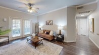 Located at 6674 Prue Rd in San Antonio, TX, this single-story 2-bedroom, 2-bathroom residence offers a well-designed layout with a comfortable and cohesive interior. The open living room is highlighted by rich hardwood-style flooring, elegant crown molding, a ceiling fan, and French doors that invite natural light and provide access to the outdoors. The kitchen is outfitted with warm wood cabinetry, granite-style countertops, a stone tile backsplash, and stainless steel appliances including a gas range and refrigerator. The primary bedroom is a spacious retreat featuring plush carpet, natural light from blinded windows, and access to a walk-in closet with multi-level wire shelving. The second bedroom also features carpet flooring, a ceiling fan, and a dedicated workspace area. Both bathrooms are finished with rich wood vanities, granite-style countertops, large mirrors, and tub-shower combinations with tile surrounds set over hardwood-style flooring. A hallway connects the rooms efficiently, completing this well-appointed single-floor layout ideal for comfortable everyday living in San Antonio.