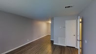 This two-story residence offers a well-organized layout across two floors, providing dedicated spaces for living, sleeping, and everyday routines. The home features two bedrooms and one and a half bathrooms, offering a comfortable and functional arrangement for its occupants.

The main living area is finished with rich, dark hardwood-style flooring that adds warmth and character to the space. Neutral gray walls provide a clean, versatile backdrop that complements a variety of décor styles. The room is equipped with both overhead ventilation and floor-level heating, ensuring year-round climate comfort. A wall-mounted thermostat and security panel near the entry door add a layer of convenience and peace of mind.

The open feel of the main level provides ample room for a living and dining arrangement, with a straightforward flow between spaces. The two-floor layout naturally separates the living areas from the private sleeping quarters, offering a degree of privacy and quiet. The half bathroom on one level adds practicality for guests, while the full bathroom serves the bedrooms. Clean white trim and baseboards throughout contribute to a crisp, well-maintained aesthetic. Overall, this home presents a tidy, move-in-ready environment with a simple and efficient design.