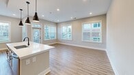 Located at 3426 Anson Street in Charlotte, NC, this well-appointed residence offers three bedrooms, five bathrooms, and a thoughtfully designed single-floor layout. The open-concept living room is bright and welcoming, featuring light hardwood-style flooring, recessed lighting, and large windows dressed with horizontal blinds that invite generous natural light and neighborhood views.

The kitchen is a standout feature, showcasing gray shaker-style cabinetry, stainless steel appliances including a French door refrigerator, a sleek cooktop with a statement range hood, and open upper shelving — all complemented by warm wood-look flooring. The bedrooms are comfortably sized, with plush carpeting, neutral walls, and well-placed windows offering outside views. The spacious primary bedroom includes access to two closets with built-in shelving and hanging rods for ample storage.

The bathrooms are elegantly finished; the primary bath features marble-look tile flooring, a dual-sink vanity with dark countertops and black hardware, framed mirrors, and a glass-enclosed shower. Secondary bathrooms offer tub-shower combinations with large-format stone tile surrounds. A private balcony extends the living space outdoors, providing open views of the surrounding Charlotte neighborhood and streetscape.
