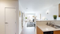 Located at 1250 E Burnside Street in Portland's vibrant Lower Buckman neighborhood, this three-bedroom, one-bathroom apartment offers a well-designed layout across a single floor. The open-concept kitchen and living area forms the heart of the unit, where warm wood cabinetry, a full suite of stainless steel appliances — including a refrigerator, range, and over-the-range microwave — and a peninsula with breakfast bar seating create a functional and inviting space. Hardwood-style flooring runs throughout the main living areas, adding warmth and continuity. The living room receives natural light through large windows fitted with horizontal blinds, offering views of the surrounding neighborhood. The three bedrooms are comfortably proportioned, each featuring neutral carpet, closet space, and windows that bring in additional daylight. The primary bedroom includes a sliding-door closet and ample room for a full bedroom setup. The shared bathroom is cleanly finished with a full soaking tub and shower combination, hardwood-style flooring, and open wall shelving. Clean white walls and a consistent modern aesthetic throughout give the unit a bright, cohesive character well-suited for urban living in Portland.