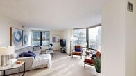 This two-bedroom, two-bathroom residence in Milwaukee's 53202 zip code offers a thoughtfully arranged single-level layout with an emphasis on natural light and urban views. The living room is a standout space, featuring expansive floor-to-ceiling windows on two walls that frame sweeping views of the Milwaukee skyline, flooding the carpeted room with daylight. The open atmosphere is well-suited for both relaxing and entertaining.

Adjacent to the living area, a defined dining space provides an intimate setting for meals, complete with its own window and ceiling light fixture. The galley-style kitchen is outfitted with warm wood cabinetry, stainless steel appliances including a full-size refrigerator, microwave, and dishwasher, and tile flooring for easy maintenance.

Both bedrooms are carpeted and offer a calm, neutral palette with windows providing city views and ample wall space. Each connects to one of two full bathrooms, one of which features a tiled tub-shower combination. Throughout the unit, light-toned walls and consistent flooring create a cohesive, understated aesthetic suited to a range of interior styles.