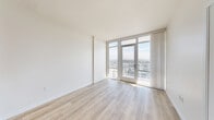Located in the heart of downtown San Diego at 1150 E Street, this modern 1-bedroom, 1-bathroom residence offers a thoughtfully designed open-concept layout. Light wood-tone flooring flows throughout, complementing the crisp white walls and creating a clean, contemporary aesthetic.

The combined living, dining, and kitchen area serves as the heart of the home. Floor-to-ceiling windows and a glass-panel balcony door flood the space with abundant natural light while framing sweeping panoramic views of the San Diego skyline. The private balcony extends the living space outdoors, offering an elevated vantage point over the city.

The kitchen is outfitted with stainless steel appliances including a refrigerator with ice maker, range, microwave, and dishwasher. White flat-front cabinetry, a light quartz countertop with an undermount sink, and a subway tile backsplash complete the polished look.

The bedroom enjoys its own impressive floor-to-ceiling window with city views, a mirrored sliding-door closet, and the same warm hardwood flooring. The bathroom features marble-tiled walls and flooring, a soaking tub with overhead shower, and a clean, minimalist finish. A dedicated laundry area and additional closet space add everyday practicality to this high-rise residence.