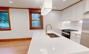Located at 1233 N Hoyne Avenue, Unit 1 in Chicago's Ukrainian Village neighborhood, this single-floor unit offers 1,570 square feet of thoughtfully designed living space across 5 bedrooms and 5 bathrooms. Rich hardwood floors and warm-toned wood trim, crown molding, and door casings are found throughout, creating a cohesive blend of classic craftsmanship and contemporary updates. The open-concept kitchen and living area serves as the heart of the home, featuring white shaker cabinetry with gold hardware, a large white quartz waterfall island with an undermount sink, stainless steel appliances including a gas range and French door refrigerator, and a striking pendant light fixture. The kitchen flows seamlessly into the living and dining area, which is framed by large windows with wood trim that invite abundant natural light. Each of the five bedrooms features light hardwood floors, recessed lighting, globe pendant fixtures, and wood-trimmed windows overlooking the surrounding neighborhood. The five bathrooms are finished with white subway tile, marble mosaic floors, and chrome fixtures — some featuring soaking tub/shower combos and others walk-in glass-enclosed showers. The primary bedroom measures 160 square feet and includes direct access to a private bathroom.