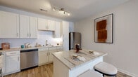 Located at 1305 Vintage Brunswick Cir in Brunswick, Georgia, this well-designed 2-bedroom, 2-bathroom residence offers a thoughtfully laid-out single-floor plan. Wood-look flooring flows throughout, lending warmth and continuity to every room.

The kitchen is a standout feature, showcasing white shaker cabinetry, a white subway tile backsplash, stainless steel appliances including a refrigerator and dishwasher, and a granite-topped breakfast bar island with seating — ideal for casual dining and entertaining. Track lighting illuminates the space effectively.

The living room is bright and inviting, with large windows that allow natural light to pour in. A bold accent wall anchors the room, complementing the open layout visible in the floor plan.

The primary bedroom offers a comfortable, well-proportioned retreat with a ceiling fan, large window, and access to a dedicated closet with wire shelving systems for organized storage. The second bedroom mirrors this functionality with its own window and ceiling fan.

Both bathrooms are clean and modern, with the primary bath featuring tile flooring, a glass-enclosed shower, a single-sink vanity with a granite countertop, and ample cabinet storage.

A dedicated in-unit laundry area accommodates a full-size washer and dryer with overhead wire shelving. Two closets provide additional storage throughout the home.