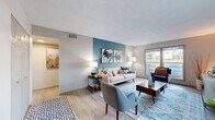 Located at 1011 River Ridge Dr in Augusta, GA, this single-story 2-bedroom, 2-bathroom home offers a thoughtfully designed layout across a comfortable footprint. The living room serves as the heart of the home, highlighted by a bold teal accent wall, light wood-style flooring, and large windows that invite natural light and outdoor views. The space flows seamlessly into the dining area, which features neutral tones and a cozy, intimate feel. The galley-style kitchen is well-equipped with white shaker cabinetry, granite countertops, stainless steel appliances including a gas range and dishwasher, and a deep undermount sink — offering both style and practicality. The spacious primary bedroom benefits from generous natural light through large windows with patterned drapes, a built-in closet, and light wood-style flooring that carries throughout. The second bedroom is equally comfortable and well-proportioned. Both bathrooms are finished with white cabinetry, granite countertops, undermount sinks, and brushed nickel hardware. Two hallways connect the rooms efficiently, contributing to a smooth and functional flow throughout the home. The overall ambiance is clean, modern, and inviting.