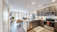 Located at Aereum in Franklin, TN, this 2-bedroom, 2-bathroom residence offers a thoughtfully designed single-floor layout with modern finishes throughout. The open-concept kitchen and living area serves as the heart of the home, featuring dark espresso cabinetry, stainless steel appliances, a tile backsplash, and a generous granite island with bar seating — ideal for both cooking and entertaining. Light wood-style flooring flows through the main living areas, complementing the bright, neutral palette. The living room is spacious and airy, highlighted by a ceiling fan, wall-mounted TV area, and full-length glass doors that open to a private balcony with outdoor views. The primary bedroom offers soft carpet flooring, large windows that invite natural light, and access to a well-organized walk-in closet featuring built-in shelving, hanging rods, and a ladder shelf unit. The second bedroom is equally comfortable with carpet flooring and natural light. Both bathrooms are finished with dark vanity cabinetry and wood-style tile flooring. A second closet provides additional storage with built-in shelving and hanging rods. This residence combines functional design with contemporary style in a desirable Franklin, TN location.