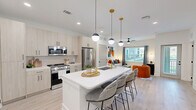 Located at 8 Duncan Ln in Arden, NC, this thoughtfully designed one-bedroom, one-bathroom residence offers a bright and modern living experience across a single floor. The open-concept kitchen and living area serves as the heart of the home, featuring light wood cabinetry extending to the ceiling, a white quartz waterfall island with seating for multiple guests, and a suite of stainless steel appliances including a gas range, over-the-range microwave, and French door refrigerator. Gold-toned pendant lights and matte black hardware add a refined contrast throughout the kitchen. The living area flows seamlessly from the kitchen, bathed in natural light from large windows dressed with patterned drapes. Light hardwood-style flooring runs throughout the entire residence, unifying the space with warmth and consistency. The bedroom is a comfortable retreat, offering a ceiling fan, natural light, and direct access to the bathroom. The full bathroom features a glass-enclosed walk-in shower with white subway tile, matte black fixtures, and light wood-look flooring. Additional highlights include multiple closets, an in-unit laundry area, and clean white walls that enhance the bright, airy ambiance of the home.