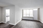 Located at 40 Tuxedo Court in Toronto's Scarborough neighbourhood, this well-appointed two-bedroom, one-bathroom unit offers a comfortable and functional layout across a single floor. Consistent grey laminate flooring flows throughout the space, lending a clean, modern aesthetic to each room.

The living areas are bright and open, benefiting from large picture windows that frame peaceful views of surrounding trees. Baseboard heating runs beneath the windows, ensuring year-round comfort. The space features two distinct living areas, providing flexibility for a dedicated lounge and dining setup.

The galley-style kitchen is efficiently designed with white cabinetry featuring brushed gold hardware, dark countertops, a stainless steel double sink, and a window that allows natural light to fill the workspace. Ample upper and lower cabinet storage adds to its practicality.

Both bedrooms are generously proportioned, each with large windows overlooking the treetops. The primary bedroom includes a closet and connects to adjacent spaces, while the second bedroom offers a quiet, versatile retreat. The full bathroom is finished with white tile surround, a soaker tub with shower, a dark-countered vanity, and tile flooring.

A connecting hallway ties all rooms together in a logical, easy-to-navigate flow, completing this well-organized and move-in-ready unit.