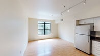 Located at 1127 18th St, Unit 326, in Sacramento's Midtown neighborhood, this third-floor apartment offers a well-designed, single-level layout with a clean, contemporary aesthetic. Light wood flooring runs throughout the main living areas, complementing the crisp white walls and creating a bright, airy atmosphere.

The open-concept living area is spacious and filled with natural light from a large picture window that frames views of the surrounding neighborhood. Track lighting overhead provides flexible illumination across the space. The living area flows seamlessly into the kitchen, which is equipped with stainless steel appliances — including a refrigerator, range, microwave, and dishwasher — white cabinetry, and green countertops, all finished with the same track lighting system for a cohesive look.

A separate bedroom offers a similarly bright environment, benefiting from its own large window with neighborhood views and continuing the light wood flooring found throughout the unit.

A utility area houses a stacked in-unit washer and dryer, providing added convenience. The bathroom is accessible from this hallway corridor, completing the functional layout of the space. Overall, the unit presents a modern, minimalist interior well-suited for comfortable urban living in Sacramento.