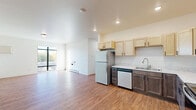 This thoughtfully designed single-floor residence offers three bedrooms, three bathrooms, and a practical layout that maximizes everyday livability. The open living area features warm hardwood-style flooring and large floor-to-ceiling windows that flood the space with natural light and provide views of the surrounding greenery, creating a bright and welcoming atmosphere.

The kitchen is a standout feature, showcasing a two-tone cabinetry design with light maple uppers and darker lower cabinets, complemented by light stone-look countertops. Stainless steel appliances — including a refrigerator, electric range with microwave hood, and dishwasher — complete the well-equipped space.

Each of the three bedrooms is finished with plush carpet flooring and benefits from natural light, with the primary bedroom offering a notably spacious footprint. The bedrooms are served by three clean, white bathrooms, each featuring a walk-in shower stall with chrome fixtures. Every bedroom includes its own dedicated closet, with wire shelving for organized storage.

A dedicated laundry room houses a full-size Whirlpool washer and dryer set, adding exceptional convenience. The hallway connects all areas seamlessly, and baseboard heating is present throughout, ensuring year-round comfort. The overall aesthetic is clean, modern, and move-in ready.
