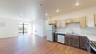 This thoughtfully designed single-floor residence offers three bedrooms, three bathrooms, and a practical layout that maximizes everyday livability. The open living area features warm hardwood-style flooring and large floor-to-ceiling windows that flood the space with natural light and provide views of the surrounding greenery, creating a bright and welcoming atmosphere.

The kitchen is a standout feature, showcasing a two-tone cabinetry design with light maple uppers and darker lower cabinets, complemented by light stone-look countertops. Stainless steel appliances — including a refrigerator, electric range with microwave hood, and dishwasher — complete the well-equipped space.

Each of the three bedrooms is finished with plush carpet flooring and benefits from natural light, with the primary bedroom offering a notably spacious footprint. The bedrooms are served by three clean, white bathrooms, each featuring a walk-in shower stall with chrome fixtures. Every bedroom includes its own dedicated closet, with wire shelving for organized storage.

A dedicated laundry room houses a full-size Whirlpool washer and dryer set, adding exceptional convenience. The hallway connects all areas seamlessly, and baseboard heating is present throughout, ensuring year-round comfort. The overall aesthetic is clean, modern, and move-in ready.