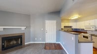 Located at 4250 South Jones Blvd. in Las Vegas, NV, this one-bedroom, two-bathroom unit offers a well-designed layout across a single floor. The entrance opens into a combined living area featuring vaulted ceilings that amplify the sense of space, soft carpeted flooring, and a cozy fireplace that serves as a focal point. Large sliding glass doors lead to an outdoor patio, filling the living area with natural light and providing outdoor access.

The kitchen is positioned adjacent to the living space and features a peninsula-style breakfast bar with dark granite-look countertops, abundant white cabinetry, a full suite of white appliances including an electric range, built-in microwave, and refrigerator, as well as warm hardwood flooring. A ceiling fan is installed nearby, adding comfort to the space.

The bedroom is generously sized with plush carpeting, vaulted ceilings, and a window with blinds that allows natural light. A private exit door leads directly to the outdoors. Two full bathrooms serve the unit, one of which includes a tub/shower combo with tile surround, dark countertops, and hardwood flooring. Cool grey tones are carried throughout the unit, contributing to a calm and cohesive aesthetic.