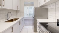 Located at 494 Avenue Rd in Toronto's desirable midtown neighbourhood, this well-appointed one-bedroom, one-bathroom unit offers a bright and functional layout across a single floor. The open living and dining area is highlighted by light-toned laminate hardwood flooring, crisp white walls, and large floor-to-ceiling vertical blinds that allow generous natural light to pour in. A sliding door leads directly to a private balcony overlooking mature trees, extending the living space outdoors. The galley-style kitchen is outfitted with clean white cabinetry featuring modern hardware, white quartz countertops, a classic subway tile backsplash, and stainless steel appliances including a refrigerator and electric range. Light tile flooring runs throughout the kitchen and hallways, which connect smoothly to the rest of the unit. The bedroom is a comfortable size, featuring mirrored sliding closet doors that reflect natural light from the window. The bathroom offers a full soaker tub with marble-style tile surround, chrome fixtures, and tile flooring, giving it a clean and polished look. Two closets provide ample storage throughout the unit. The overall aesthetic is neutral and modern, creating a bright, move-in-ready space.
