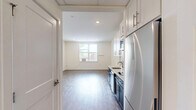 Located at 400 S 40th St, Unit 410, in Philadelphia's West Philadelphia neighborhood, this studio unit offers a well-designed layout that maximizes every square foot of its compact footprint. The open living area features light-toned hardwood flooring and neutral white walls, creating a bright and airy atmosphere enhanced by a window that invites natural light and outdoor views.

The kitchen is a standout feature, showcasing a striking two-tone design with navy blue lower cabinets and crisp white upper cabinets accented by a light grey subway tile backsplash. Stainless steel appliances — including a refrigerator, over-the-range microwave, dishwasher, and electric cooktop — are seamlessly integrated alongside a single-basin undermount sink with a modern faucet and clean white countertops. The kitchen flows naturally into the main living space through a wide corridor, making the unit feel connected and functional.

The bathroom maintains the unit's clean aesthetic with white walls, classic hexagonal mosaic tile flooring, and accessibility-friendly grab bars in the shower area. The overall design emphasizes simplicity and practicality, making this a well-appointed unit suited for efficient urban living in Philadelphia.