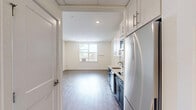 Located at 400 S 40th St, Unit 410, in Philadelphia's West Philadelphia neighborhood, this studio unit offers a well-designed layout that maximizes every square foot of its compact footprint. The open living area features light-toned hardwood flooring and neutral white walls, creating a bright and airy atmosphere enhanced by a window that invites natural light and outdoor views.

The kitchen is a standout feature, showcasing a striking two-tone design with navy blue lower cabinets and crisp white upper cabinets accented by a light grey subway tile backsplash. Stainless steel appliances — including a refrigerator, over-the-range microwave, dishwasher, and electric cooktop — are seamlessly integrated alongside a single-basin undermount sink with a modern faucet and clean white countertops. The kitchen flows naturally into the main living space through a wide corridor, making the unit feel connected and functional.

The bathroom maintains the unit's clean aesthetic with white walls, classic hexagonal mosaic tile flooring, and accessibility-friendly grab bars in the shower area. The overall design emphasizes simplicity and practicality, making this a well-appointed unit suited for efficient urban living in Philadelphia.