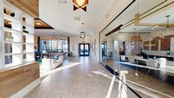 Located at 1035 Strensall Lane in Charlotte, NC, this amenity center at Sonderly at the Reservoir offers a thoughtfully designed, single-floor community space that blends modern aesthetics with practical functionality. The welcoming entrance features large-format tile flooring, soaring ceilings, decorative pendant lighting, warm wood-paneled accent walls, and built-in shelving — setting an inviting tone from the moment you arrive. A glass-walled conference or leasing office sits just off the entry corridor, bathed in natural light.

The expansive living lounge is the heart of the space, showcasing coffered ceilings with rich wood inlays, floor-to-ceiling windows that flood the room with natural light and exterior views, a fireplace, and an eclectic mix of contemporary seating. A billiards table, bar-height dining, and a beverage station make this an ideal gathering space for residents.

The two fitness rooms are well-appointed and distinct in purpose. One room features cardio equipment including treadmills and ellipticals alongside a textured tile accent wall and large windows. The second room is dedicated to strength and functional training, housing cable machines, kettlebells, medicine balls, battle ropes, and cycling and rowing equipment. A glass-panel garage door opens the space to the outdoors, enhancing ventilation and ambiance throughout the fitness area.