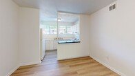 Located at 2075 Langhorne Rd in Lynchburg, Virginia, this two-bedroom, one-bathroom unit offers a practical and efficient single-floor layout. The space is thoughtfully arranged to maximize functionality throughout.

The kitchen is a standout feature, equipped with white cabinetry with gold hardware, a white electric range, a refrigerator, and light wood-look flooring. A dark-countered breakfast bar separates the kitchen from the adjacent living area, creating an open, connected feel. Natural light filters in through a window fitted with blinds, brightening the workspace.

The living area continues the wood-look flooring from the kitchen and offers a clean, open canvas with neutral walls and access to natural light through large windows overlooking the surrounding landscape.

Both bedrooms are carpeted with neutral tones and feature white walls, providing a bright and comfortable environment. The spacious primary bedroom includes a window with outdoor views and ample wall space. The second bedroom also benefits from natural light through dual windows.

The bathroom is finished with classic white square tile surrounding a full bathtub and shower combination, fitted with chrome fixtures.

Throughout the unit, the clean, neutral palette and consistent finishes create a cohesive, move-in-ready atmosphere suited for comfortable everyday living.