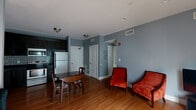 Located at 703 N Walnut St in Bloomington, Indiana, this two-bedroom, two-bathroom single-floor residence offers a practical and comfortable layout. The open-concept living and dining area is finished with warm hardwood floors and cool gray walls, creating a welcoming atmosphere. French doors at one end of the living area bring in natural light and provide outdoor access. The kitchen is well-appointed with dark espresso cabinetry, a mosaic tile backsplash, dark countertops, and a full suite of stainless steel appliances including a refrigerator, range, and over-the-range microwave. Both bedrooms feature hardwood flooring and neutral tones; the primary bedroom is a comfortable size with a dedicated closet, while the second bedroom offers two windows for natural light and its own closet. The two bathrooms are finished with dark slate tile flooring and walk-in showers accented by mosaic tile detailing. Additional conveniences include in-unit laundry and multiple closets throughout. The overall design is cohesive, blending functional finishes with a clean, understated aesthetic well-suited for everyday living.