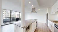 Located at 1500 Haro Street in Vancouver's desirable West End neighbourhood, this one-bedroom, one-bathroom residence offers a well-designed layout across a single floor. Light wood-tone flooring flows throughout the entire unit, lending a clean, cohesive aesthetic to every room.

The open-concept kitchen and living area forms the heart of the home. The kitchen is outfitted with crisp white cabinetry extending to the ceiling, a grey quartz-style countertop, a subway tile backsplash, stainless steel appliances including a full-size refrigerator, a built-in oven, a microwave, and a central island with a cooktop and integrated range hood. The living area benefits from floor-to-ceiling sliding glass doors that open onto a private balcony, filling the space with natural light and offering views of the surrounding cityscape.

The bedroom is a comfortable, well-proportioned retreat featuring large windows that frame views of mature trees and neighbouring buildings, along with a mirrored closet that enhances the sense of space.

The bathroom is finished with a dark wood vanity, white quartz countertop, an undermount sink with modern chrome fixtures, a large mirror, and a tiled shower enclosure.

Throughout the unit, white walls, recessed lighting, and neutral finishes contribute to a bright, contemporary ambiance.
