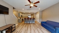 This well-appointed two-story home offers four bedrooms and four and a half bathrooms across a thoughtfully designed floor plan. The main level features an open-concept living and dining area with light-toned hardwood-style flooring, neutral taupe walls, and ceiling fans with integrated lighting that enhance airflow and comfort. A front-facing window fills the living room with natural light, creating a bright and welcoming atmosphere.

The kitchen is a standout feature, boasting gray shaker-style cabinetry, crisp white countertops, a double-basin stainless steel sink, and a full suite of stainless steel appliances including a range, microwave, and dishwasher. A spacious island with bar seating comfortably accommodates multiple guests, making it ideal for entertaining. The staircase is conveniently accessible from the main living area.

The bedrooms are generously sized, each featuring ceiling fans, hardwood-style flooring, and windows that invite natural light. The bathrooms are clean and functional, equipped with tub-shower combinations and brushed nickel fixtures. Throughout the home, the consistent neutral color palette and modern finishes create a cohesive, move-in-ready aesthetic suited for comfortable everyday living.