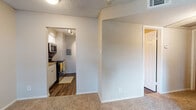 This single-story unit offers a practical and well-organized layout designed for comfortable everyday living. The kitchen is efficiently arranged with white cabinetry, light stone-finish countertops, a stainless steel refrigerator, dishwasher, and a gas range with an overhead microwave. Wood-look flooring runs throughout the kitchen and connecting areas, providing a clean, durable surface. An electrical panel is conveniently integrated into the kitchen space, and track lighting ensures the area is well-lit.

The living area transitions from wood-look flooring to plush wall-to-wall carpeting, creating a comfortable, cozy atmosphere. A hallway connects the main living space to the rest of the unit, with carpeted flooring continuing into the bedrooms. Each bedroom features ceiling fans with light fixtures, neutral-toned walls, and windows fitted with horizontal blinds that allow natural light to filter in while maintaining privacy. Views from the windows overlook surrounding greenery.

The bathroom includes wood-look flooring, a bright, open feel with access to adjacent spaces, and a textured wall finish consistent with the rest of the unit. Throughout, textured ceilings add a consistent design element, and neutral wall tones create a clean, understated ambiance suited to a variety of furnishing styles.
