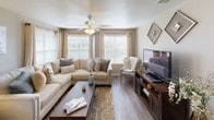 This single-floor residence offers a thoughtfully designed layout with a warm, neutral color palette throughout. The kitchen is outfitted with white cabinetry, light countertops, stainless steel appliances including a range with overhead ventilation, and a breakfast bar with seating — ideal for casual dining. An adjacent laundry area and walk-in pantry provide practical storage solutions just steps away.

The living room is a bright, welcoming space featuring wood-style flooring, a ceiling fan, and multiple windows that allow generous natural light to fill the room. Nearby, a dedicated dining area offers an intimate setting with a pendant light fixture and a large window overlooking the outdoors.

The primary bedroom features plush carpeting, a ceiling fan, and a bay window area with a built-in bench seat, creating a comfortable reading nook. A walk-in closet and en-suite bathroom with a tub-shower combination complete the suite. The second bedroom is equally comfortable, with soft carpet, a ceiling fan, and ample natural light. A full bathroom with a tub-shower combo serves the additional bedroom. Throughout the residence, wood-style and tile flooring in common areas contrast beautifully with the carpeted bedrooms, lending a cohesive and polished aesthetic.