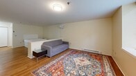 Located at 800 James Ave in Scranton, Pennsylvania, this studio unit offers a thoughtfully designed single-floor layout that efficiently combines living, sleeping, and kitchen functions within a cozy, open-plan footprint.

The kitchen is outfitted with warm-toned wood cabinetry, dark granite countertops, and a full suite of stainless steel appliances, including an electric range with an over-the-range microwave and a full-size refrigerator. A pendant light adds a polished accent above the counter workspace, while under-cabinet lighting enhances visibility throughout the galley-style kitchen.

The open living and sleeping area flows seamlessly from the kitchen, anchored by warm hardwood-style flooring throughout. A low partition subtly separates the sleeping space from the living area, creating a sense of defined zones within the open layout. A large window at the far end of the room fills the space with natural light and frames a leafy outdoor view, contributing to a bright and calm ambiance. A baseboard heating unit runs along the wall, ensuring comfort year-round.

Sliding closet doors provide convenient storage, while an additional door leads to a separate bathroom area. The neutral wall tones and clean white ceiling keep the atmosphere open and inviting, making this a functional and comfortable studio in Scranton, PA.